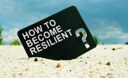 card inside sand with words how to become resilient