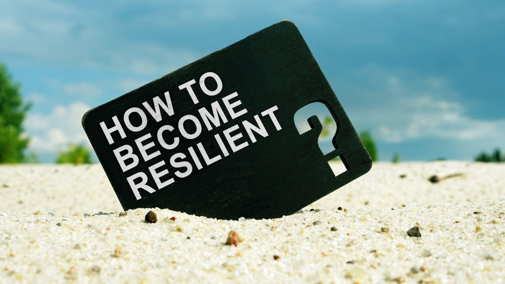 card inside sand with words how to become resilient